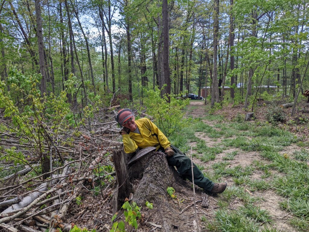 Glen sitting smiling on tree stump